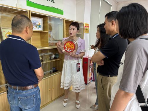 番禺区康园中心徐鸣主任向花都区残联一行介绍学员手工艺品