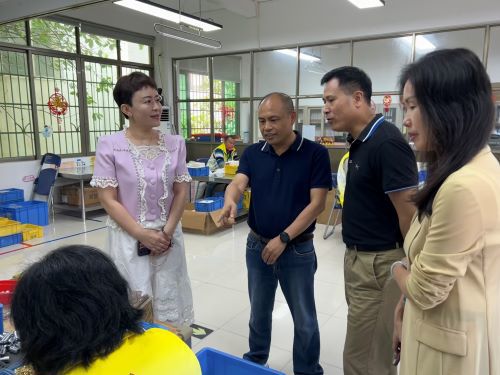 番禺区残联副理事长郑月利（右二）向花都区残联一行介绍示范站学员的辅助性就业训练开展情况